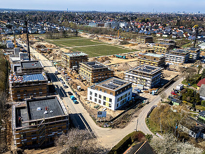 Großflächige Baustelle mit Wohngebäuden im Bau, Kränen, Erdarbeiten und umliegender Bebauung