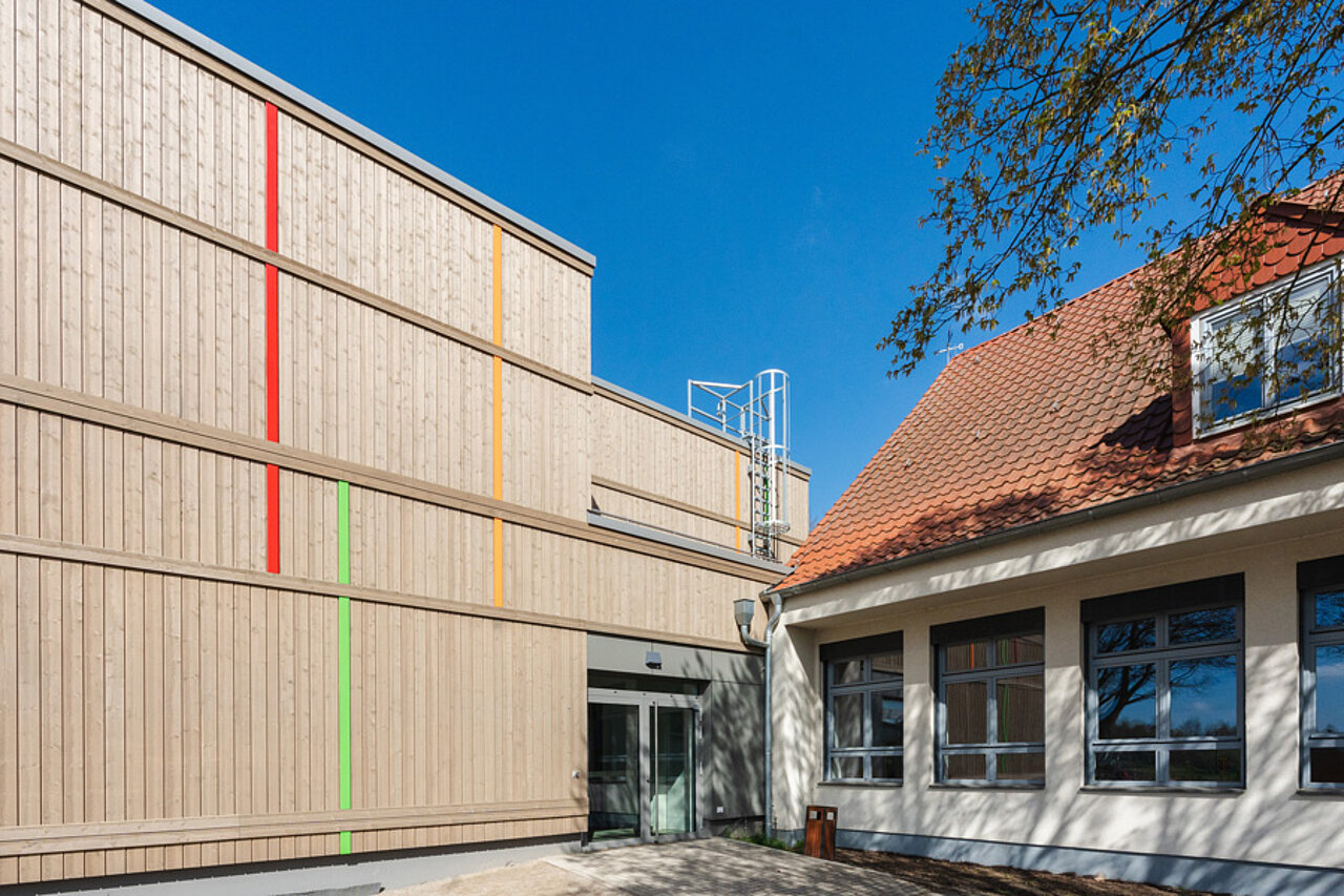 Anschluss von Schulneubau mit Holzfassade an Bestandsgebäude