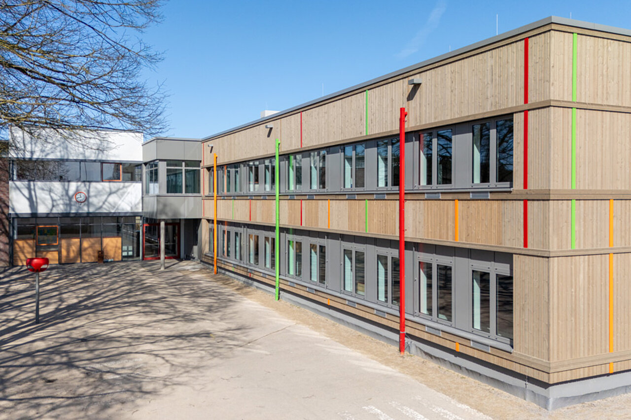 Holzfassade des Schulneubaus mit farbigen Aluminiumelementen